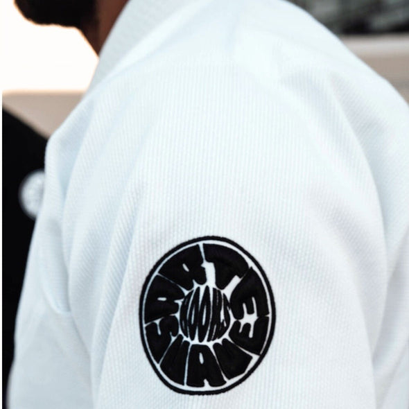 White Pantera Negra BJJ Gi sleeve with black circular ‘HOOKS’ patch, symbolizing premium martial arts apparel